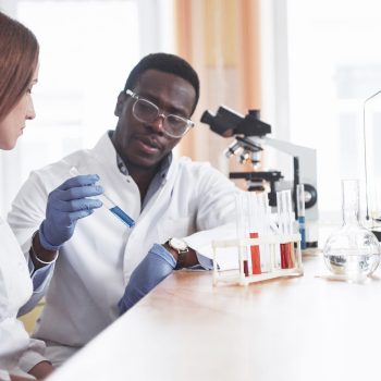 Médico com amostra de exame conversando com sua assitente no laboratório